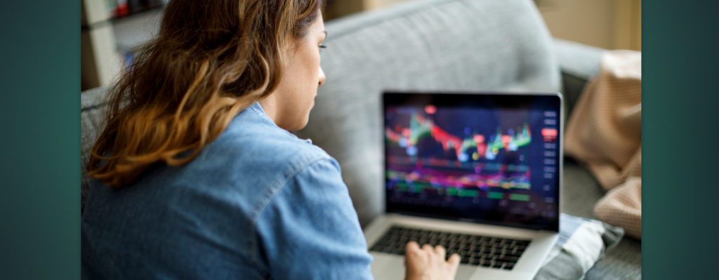 Female looking at stock market while sitting on couch